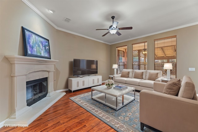 living room with visible vents, wood finished floors, crown molding, and a glass covered fireplace