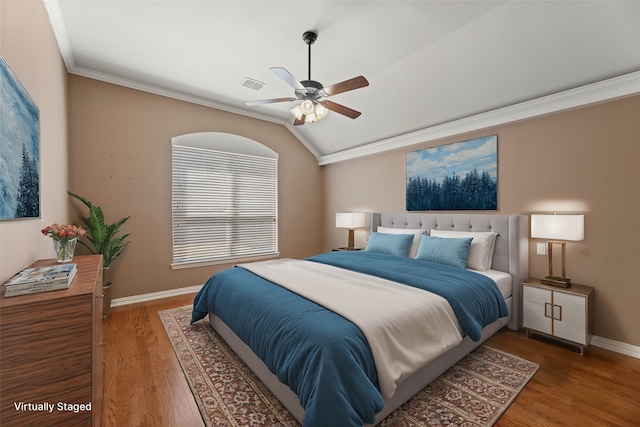 bedroom with vaulted ceiling, wood finished floors, baseboards, and ornamental molding