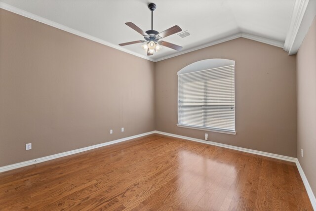 empty room with a ceiling fan, wood finished floors, visible vents, baseboards, and vaulted ceiling