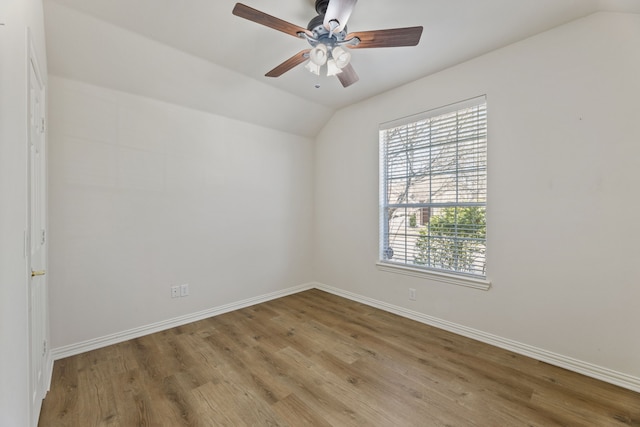 spare room featuring baseboards, wood finished floors, a ceiling fan, and vaulted ceiling