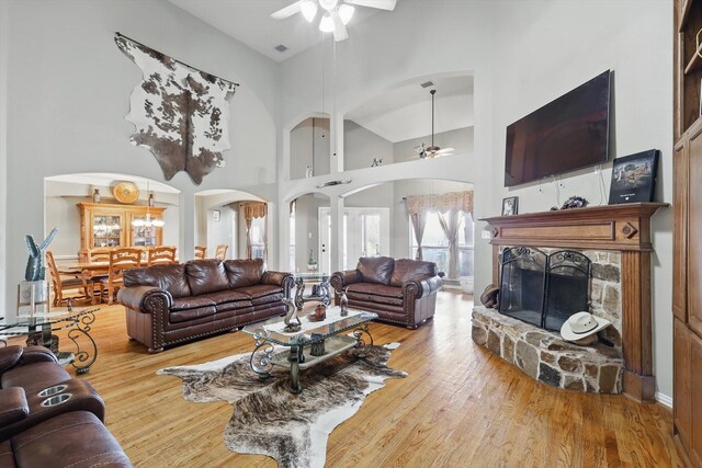 living room with wood finished floors, arched walkways, a fireplace, and a ceiling fan