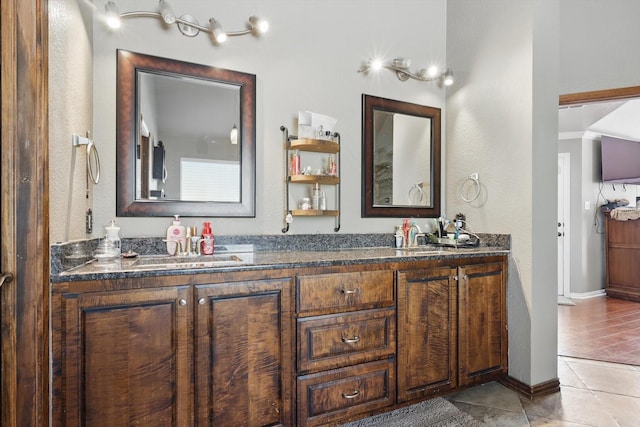 full bathroom with tile patterned flooring, double vanity, baseboards, and a sink