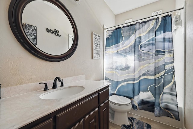 full bath featuring toilet, vanity, and a textured wall