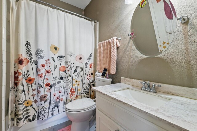 bathroom featuring vanity, toilet, and a textured wall