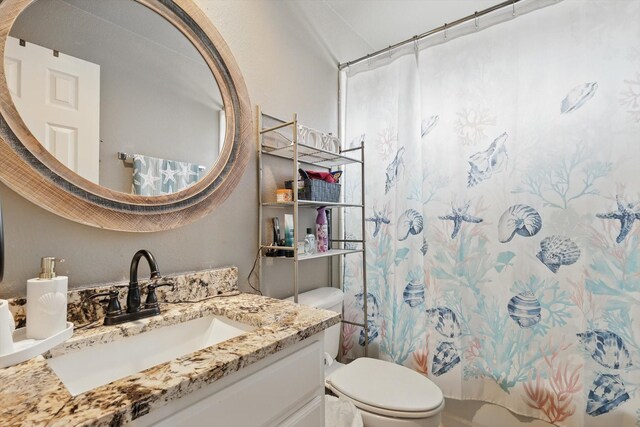 bathroom featuring vanity, shower / bath combination with curtain, and toilet