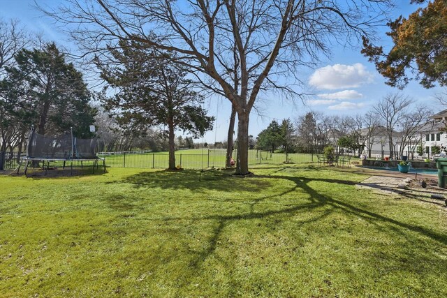 view of yard with a trampoline and fence