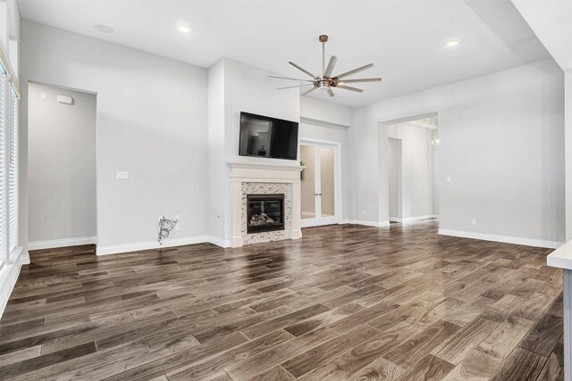 unfurnished living room featuring ceiling fan, baseboards, wood finished floors, and a tile fireplace