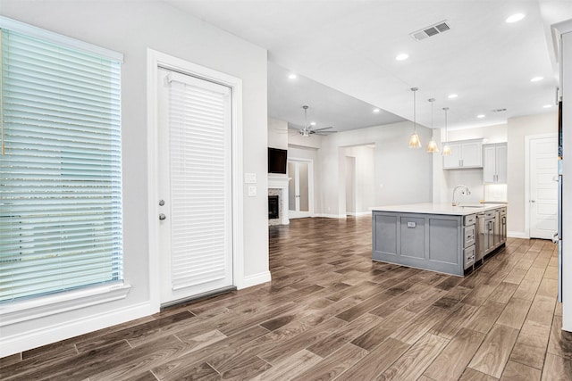 kitchen featuring visible vents, gray cabinetry, open floor plan, dark wood-style floors, and a fireplace