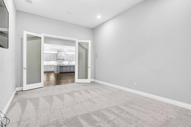 unfurnished bedroom featuring carpet flooring, french doors, ensuite bathroom, and baseboards