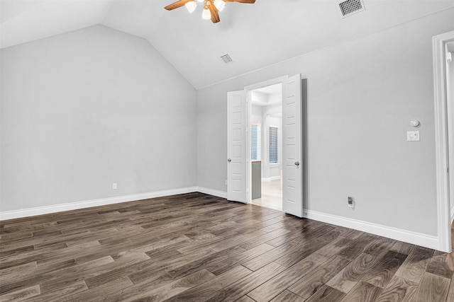 unfurnished bedroom featuring visible vents, dark wood-type flooring, baseboards, vaulted ceiling, and a ceiling fan