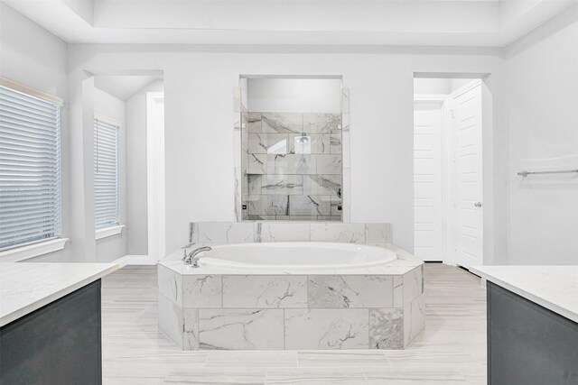 full bath featuring vanity, a bath, and a marble finish shower