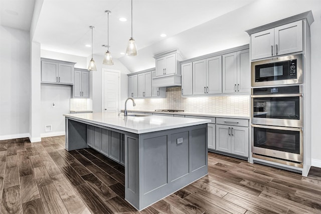 kitchen with dark wood-type flooring, light countertops, gray cabinets, and appliances with stainless steel finishes