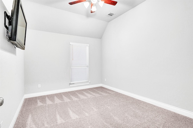 spare room with visible vents, baseboards, carpet, and vaulted ceiling