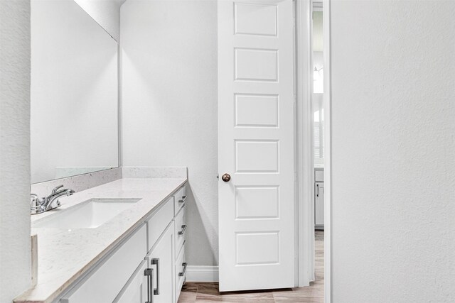 bathroom featuring vanity, wood finished floors, baseboards, and a textured wall