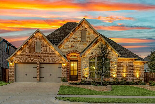 french provincial home featuring concrete driveway, a front lawn, a garage, stone siding, and brick siding