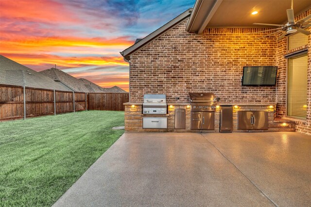 view of patio / terrace with grilling area, a fenced backyard, an outdoor kitchen, and a ceiling fan