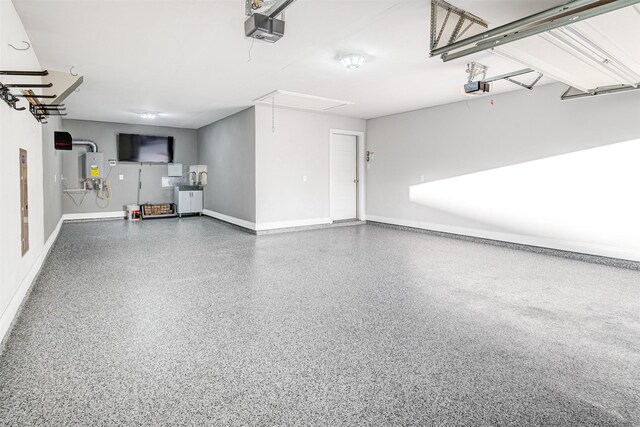 garage featuring a garage door opener, baseboards, and electric water heater