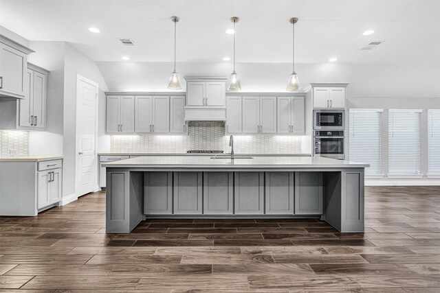 kitchen featuring built in microwave, a large island, oven, and light countertops