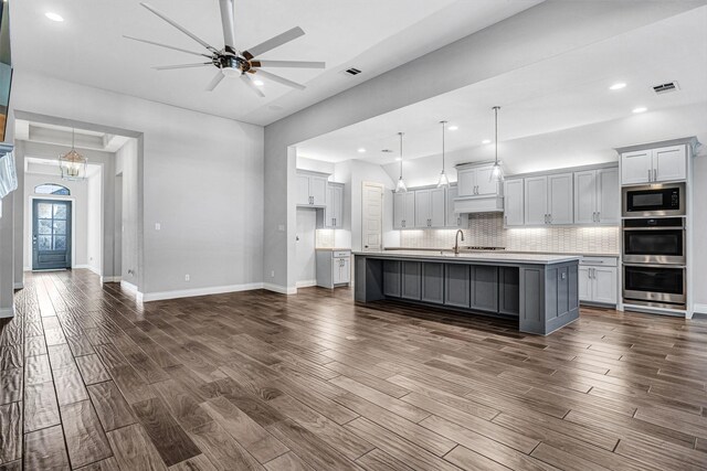 kitchen featuring tasteful backsplash, dark wood-type flooring, black microwave, light countertops, and ceiling fan with notable chandelier