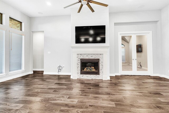 unfurnished living room featuring baseboards, wood finished floors, a ceiling fan, and a tile fireplace