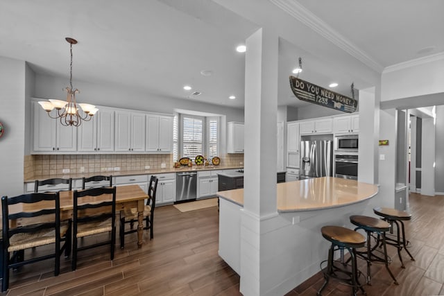 kitchen featuring dark wood-style flooring, stainless steel appliances, white cabinets, a notable chandelier, and tasteful backsplash