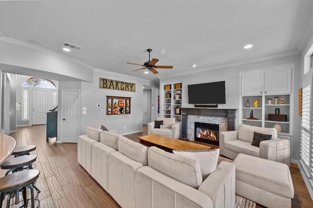 living area featuring visible vents, wood finished floors, and crown molding