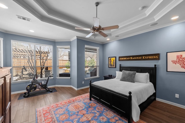 bedroom featuring a raised ceiling, wood finished floors, and visible vents