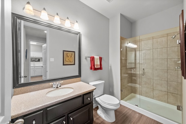 full bath featuring a stall shower, toilet, vanity, and wood finished floors