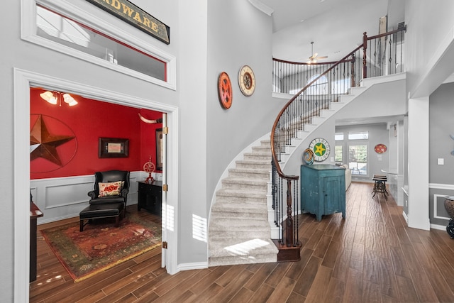 entrance foyer with stairway, baseboards, a towering ceiling, and wood finished floors