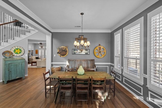 dining room with dark wood finished floors, visible vents, ceiling fan with notable chandelier, and crown molding