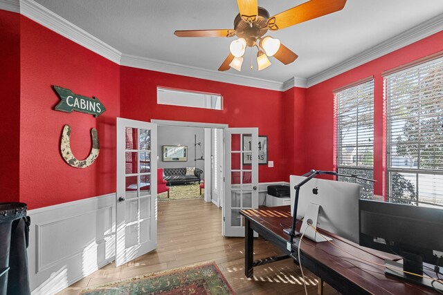 home office featuring crown molding, ceiling fan, a wainscoted wall, french doors, and wood finished floors