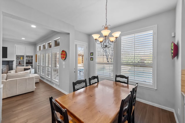 dining room with wood finished floors, baseboards, a fireplace, recessed lighting, and a chandelier