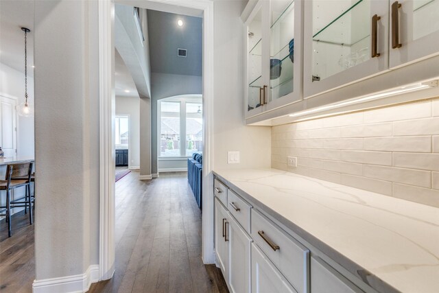 bar featuring baseboards, visible vents, dark wood finished floors, pendant lighting, and backsplash