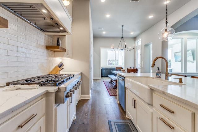 kitchen with dark wood-type flooring, custom range hood, hanging light fixtures, stainless steel appliances, and a sink