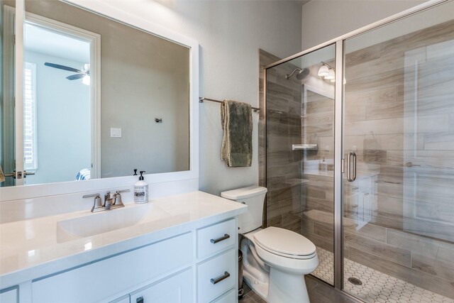 full bathroom with a ceiling fan, vanity, toilet, and a shower stall