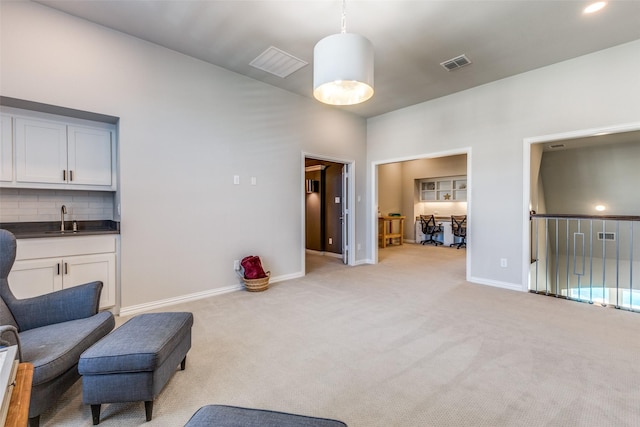 living area featuring indoor wet bar, light colored carpet, visible vents, and baseboards