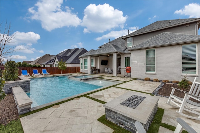 view of swimming pool with a fire pit, a pool with connected hot tub, a fenced backyard, and a patio area