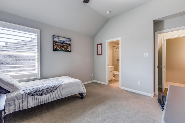 carpeted bedroom featuring ensuite bath, baseboards, and vaulted ceiling