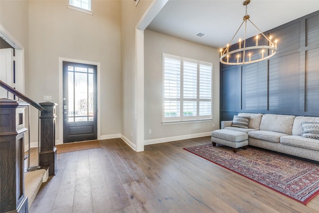 foyer with baseboards, wood-type flooring, visible vents, and a chandelier