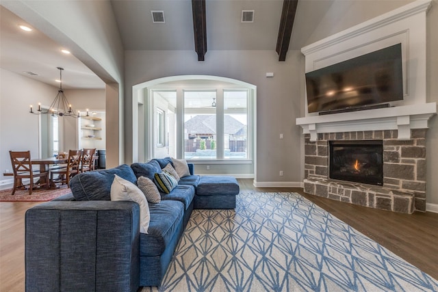 living room featuring a fireplace, beam ceiling, wood finished floors, and visible vents