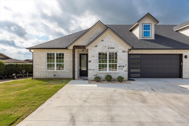 view of front of property featuring driveway, an attached garage, a front lawn, and a shingled roof