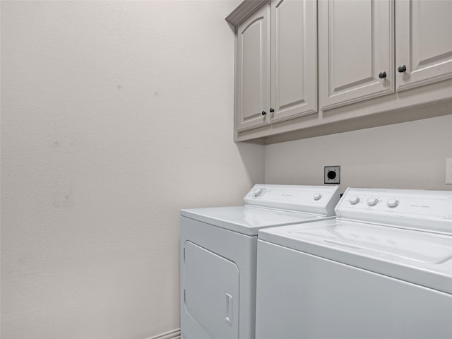 washroom with washing machine and clothes dryer, cabinet space, and baseboards