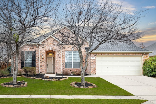 view of front of home featuring a front lawn, concrete driveway, a shingled roof, a garage, and brick siding