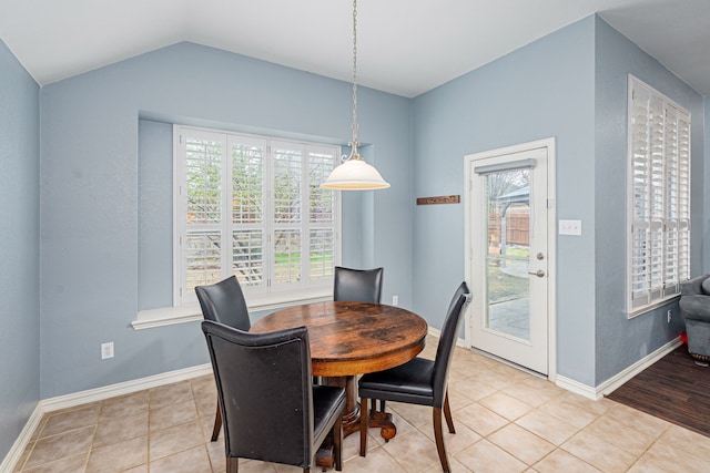 dining area featuring light tile patterned floors, lofted ceiling, and baseboards