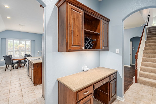 kitchen featuring a sink, lofted ceiling, light countertops, and light tile patterned floors