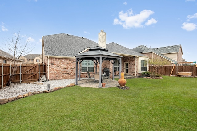 rear view of property featuring a patio, a chimney, a gazebo, a lawn, and brick siding