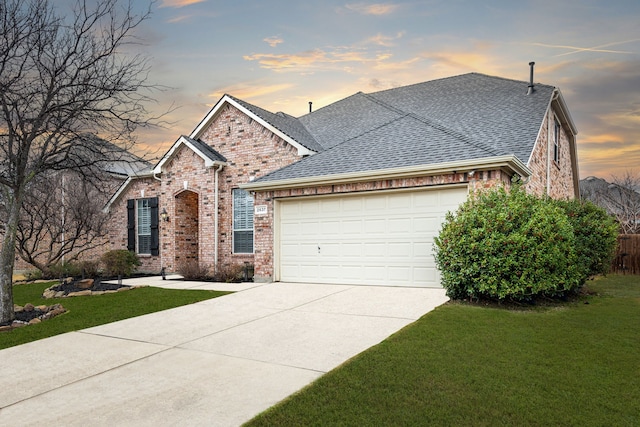 view of front of home with an attached garage, a shingled roof, a front lawn, concrete driveway, and brick siding