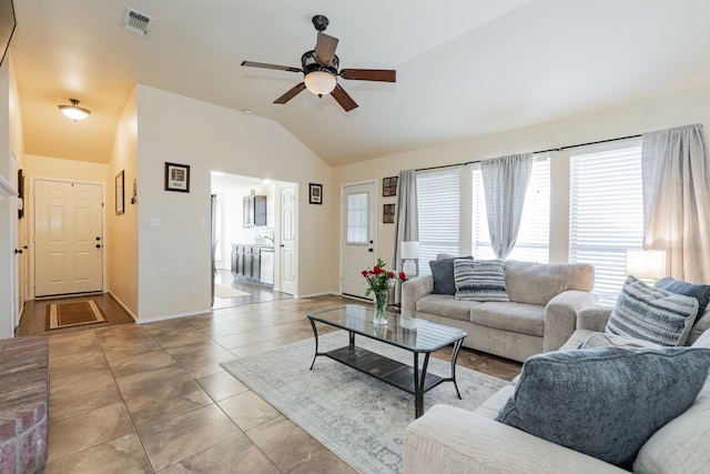 living area featuring visible vents, baseboards, lofted ceiling, light tile patterned floors, and a ceiling fan