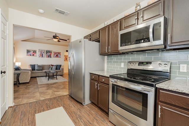 kitchen with wood finished floors, visible vents, stainless steel appliances, decorative backsplash, and dark brown cabinets