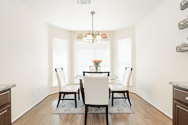 dining room with a chandelier, visible vents, light wood-type flooring, and baseboards